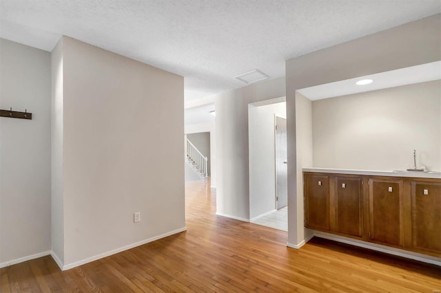 unfurnished room featuring a textured ceiling, light hardwood / wood-style flooring, and sink