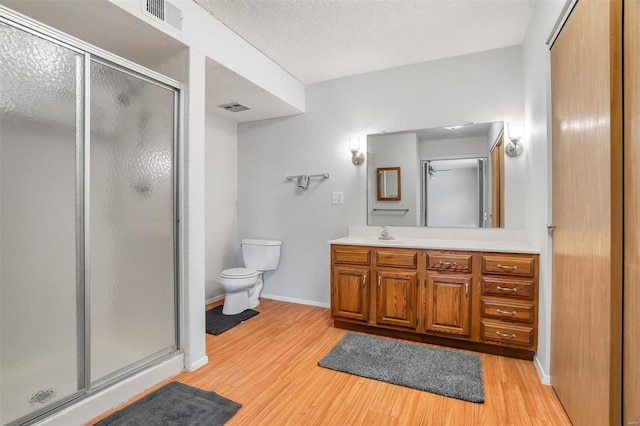 bathroom with vanity, toilet, hardwood / wood-style floors, and a shower with door