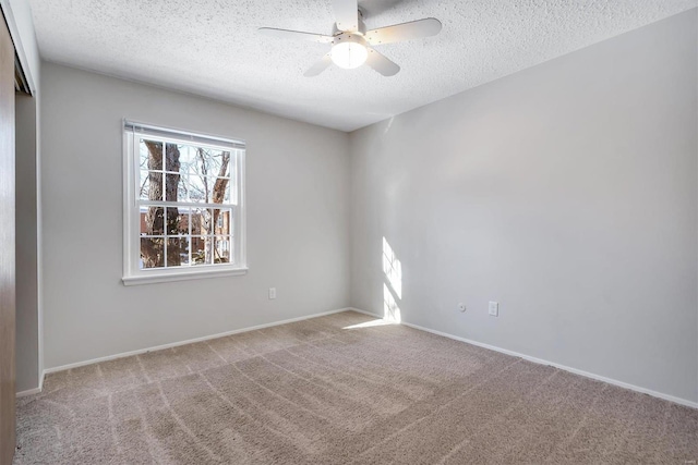 empty room featuring ceiling fan, light colored carpet, and a textured ceiling