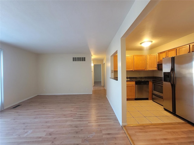 kitchen with appliances with stainless steel finishes, dark countertops, visible vents, and light wood-style floors