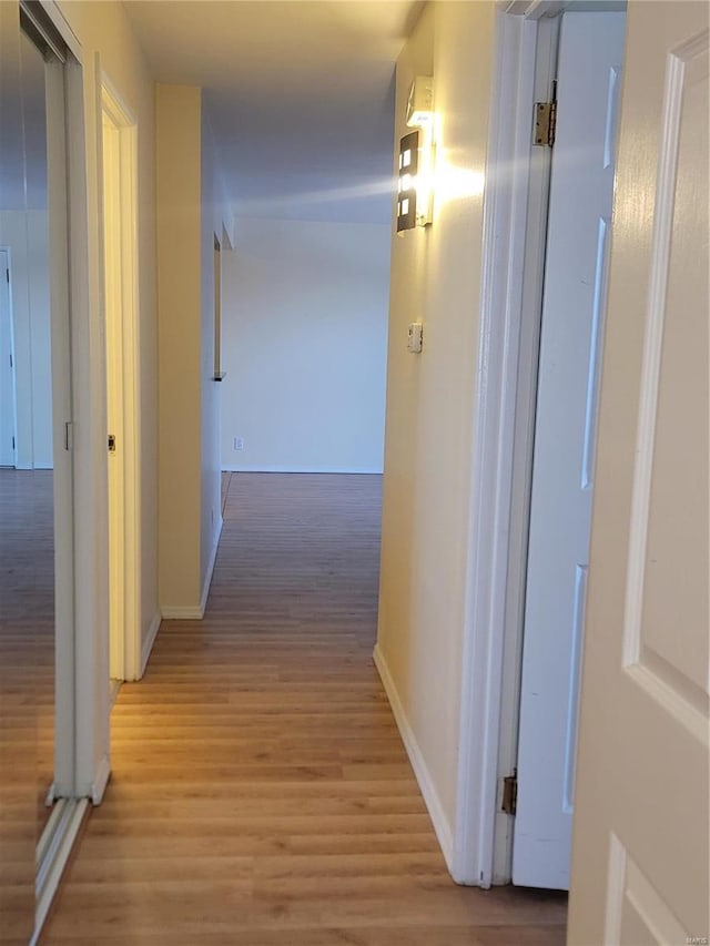 hall with light wood-style floors and baseboards