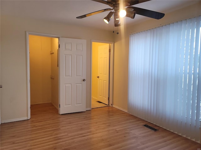 unfurnished bedroom featuring light wood-style floors, visible vents, ceiling fan, and baseboards