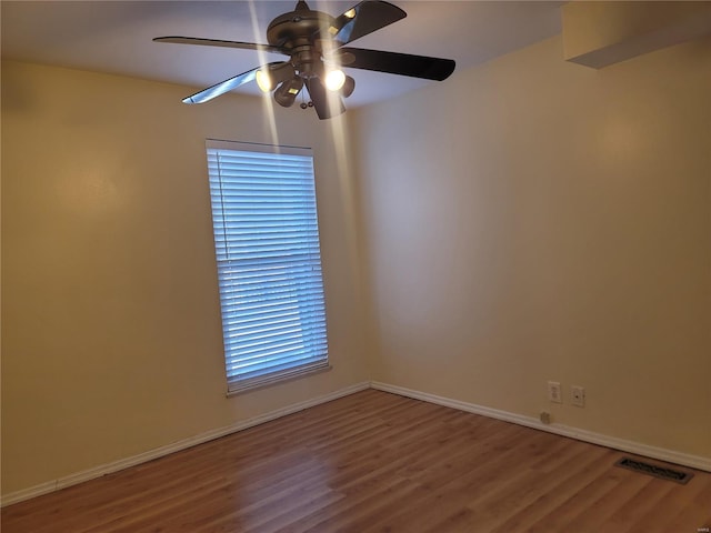 empty room with baseboards, visible vents, ceiling fan, and wood finished floors