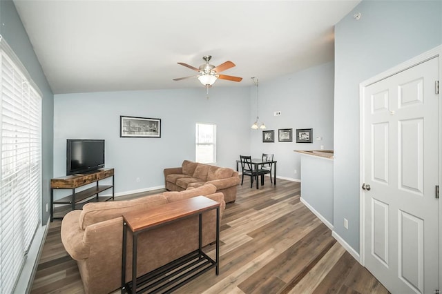 living area featuring baseboards, wood finished floors, a ceiling fan, and vaulted ceiling