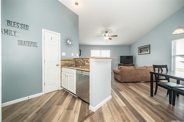 kitchen with dark wood finished floors, a sink, a peninsula, and stainless steel dishwasher