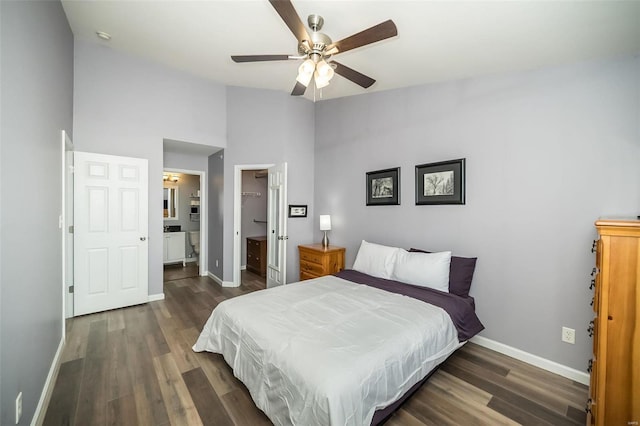 bedroom featuring wood finished floors, baseboards, a ceiling fan, lofted ceiling, and a walk in closet