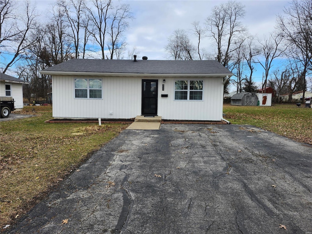 ranch-style home featuring a storage shed and a front lawn