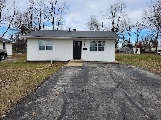 ranch-style home featuring a storage shed and a front lawn