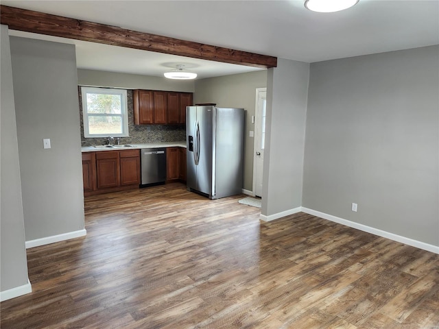 kitchen featuring sink, tasteful backsplash, beamed ceiling, dark hardwood / wood-style flooring, and stainless steel appliances