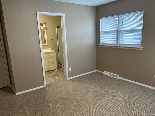 unfurnished bedroom featuring light colored carpet and connected bathroom