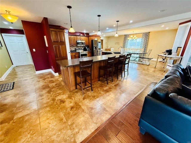 kitchen featuring a center island, an inviting chandelier, pendant lighting, a kitchen bar, and appliances with stainless steel finishes