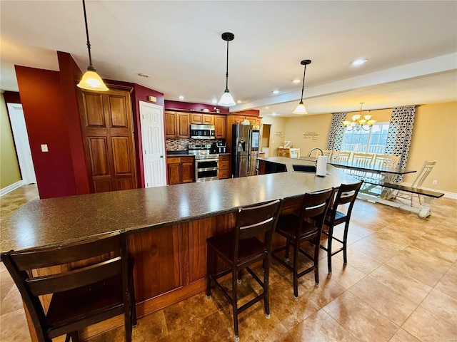 kitchen with sink, tasteful backsplash, a notable chandelier, a breakfast bar, and appliances with stainless steel finishes