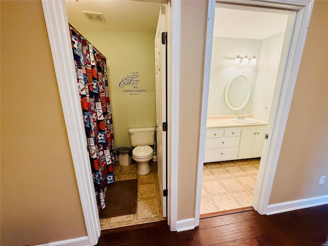 bathroom with wood-type flooring, vanity, and toilet