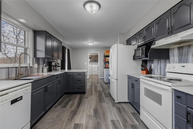 kitchen featuring washing machine and clothes dryer, sink, tasteful backsplash, dark hardwood / wood-style floors, and white appliances