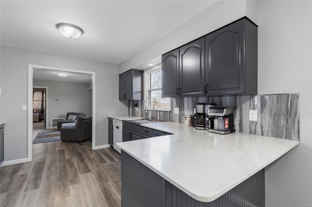 kitchen with kitchen peninsula, decorative backsplash, sink, wood-type flooring, and dishwasher