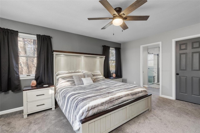 bedroom with ceiling fan, light colored carpet, ensuite bathroom, and multiple windows