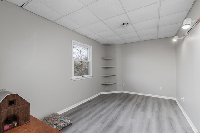 empty room with a drop ceiling and light wood-type flooring