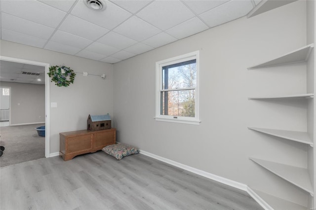 spare room featuring light hardwood / wood-style flooring and a drop ceiling