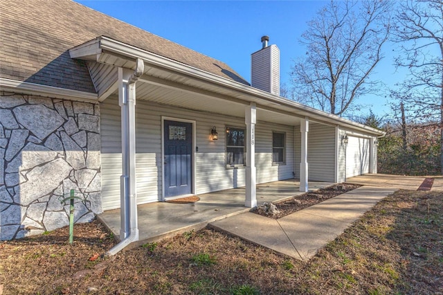 doorway to property with covered porch and a garage