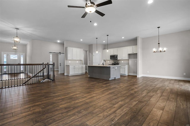 unfurnished living room with ceiling fan with notable chandelier, dark hardwood / wood-style floors, and sink