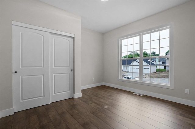 unfurnished bedroom with dark hardwood / wood-style flooring and a closet