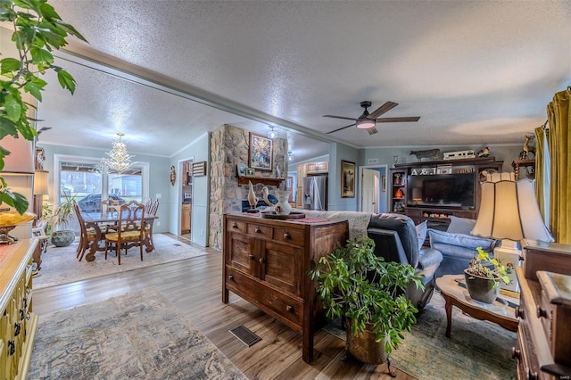 living room with a textured ceiling, crown molding, light hardwood / wood-style floors, and ceiling fan with notable chandelier