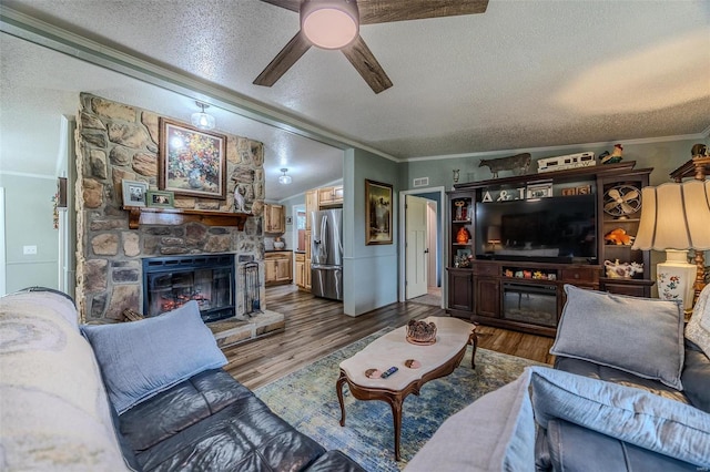 living room featuring a textured ceiling, crown molding, a fireplace, and hardwood / wood-style floors