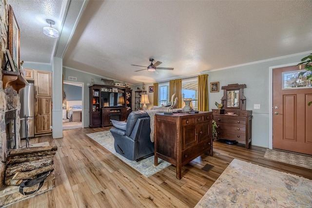 living room with a textured ceiling, light wood-type flooring, ceiling fan, and crown molding