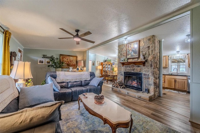 living room featuring hardwood / wood-style flooring, sink, ornamental molding, and a textured ceiling