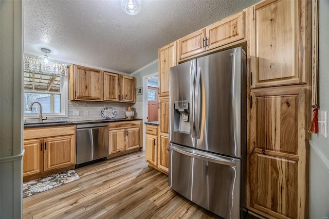 kitchen featuring decorative backsplash, appliances with stainless steel finishes, ornamental molding, sink, and light hardwood / wood-style floors