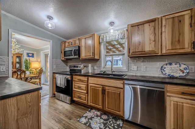 kitchen with tasteful backsplash, stainless steel appliances, vaulted ceiling, sink, and light hardwood / wood-style flooring