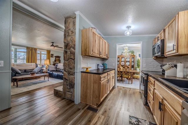 kitchen featuring decorative backsplash, appliances with stainless steel finishes, ceiling fan, crown molding, and wood-type flooring