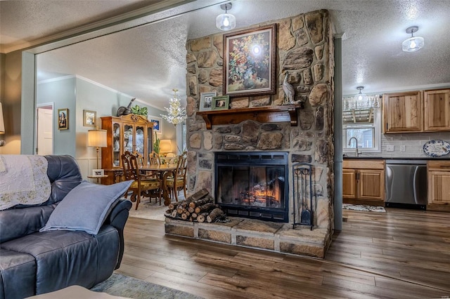 living room featuring dark hardwood / wood-style flooring, a stone fireplace, crown molding, and sink