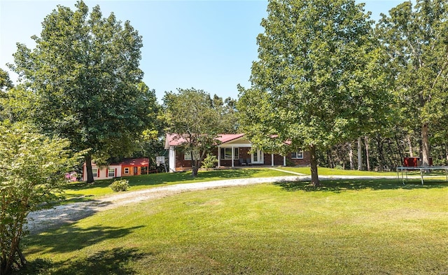 view of front of home featuring a front yard, a trampoline, and an outdoor structure