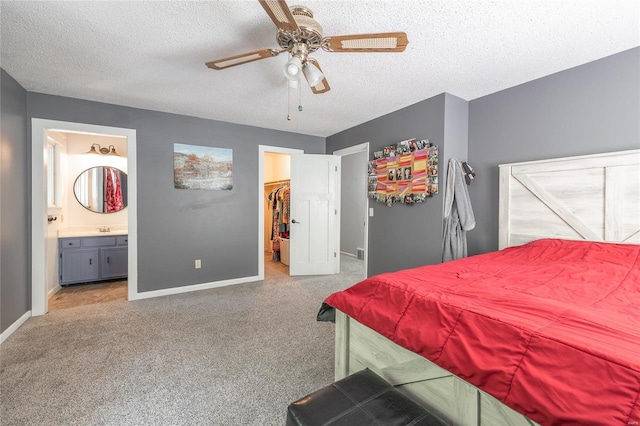 bedroom with ensuite bathroom, a walk in closet, ceiling fan, a textured ceiling, and a closet