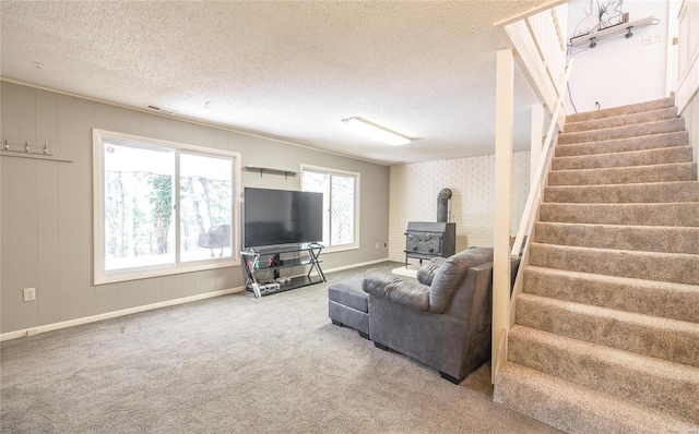 carpeted living room with a wood stove and a textured ceiling