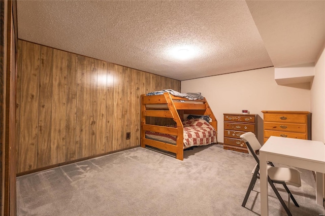 bedroom with carpet flooring, wood walls, and a textured ceiling