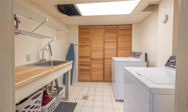 laundry room featuring washing machine and dryer, sink, and light tile patterned floors