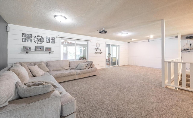 carpeted living room featuring wooden walls and a textured ceiling