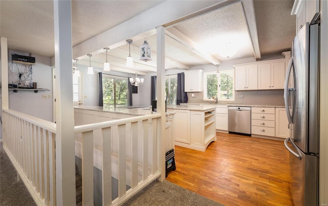 kitchen featuring a center island, light hardwood / wood-style flooring, beamed ceiling, white cabinetry, and stainless steel appliances