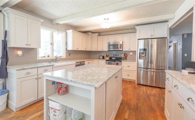 kitchen with stainless steel appliances, sink, beam ceiling, white cabinets, and a center island