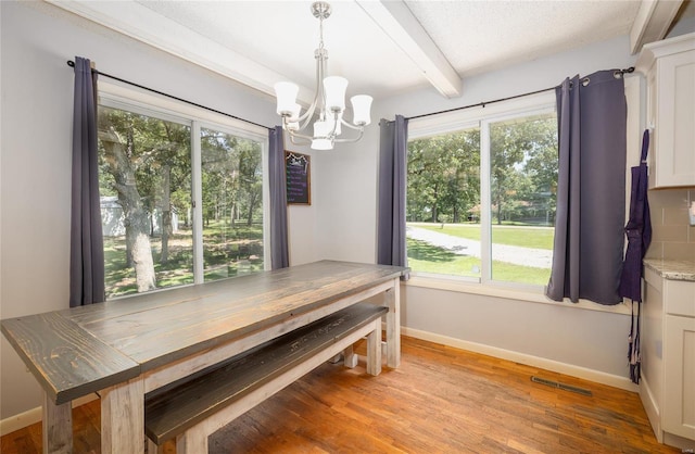 dining space with beamed ceiling, light wood-type flooring, a textured ceiling, and a notable chandelier