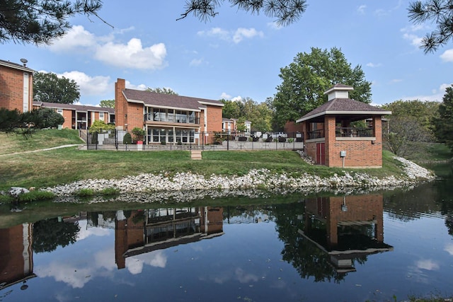 rear view of property featuring a gazebo, a water view, and a lawn