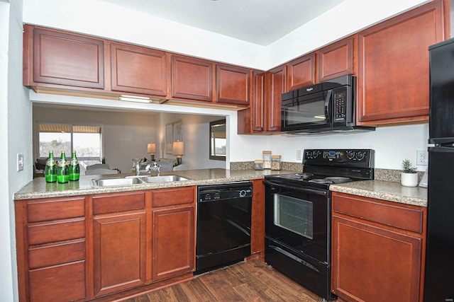 kitchen with dark hardwood / wood-style flooring, light stone counters, sink, and black appliances