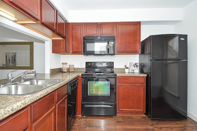 kitchen featuring dark hardwood / wood-style flooring, sink, dark stone countertops, and black appliances