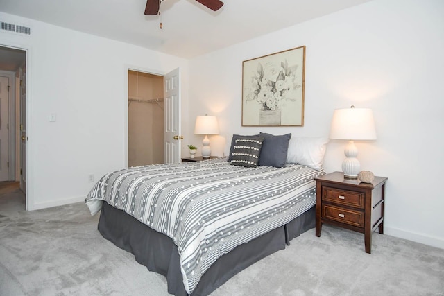 bedroom with a walk in closet, ceiling fan, a closet, and light carpet