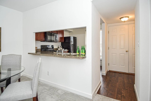 kitchen featuring kitchen peninsula, sink, black appliances, and dark hardwood / wood-style flooring