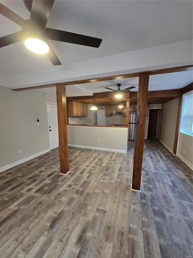 basement with a textured ceiling, dark hardwood / wood-style flooring, stainless steel refrigerator, and ceiling fan