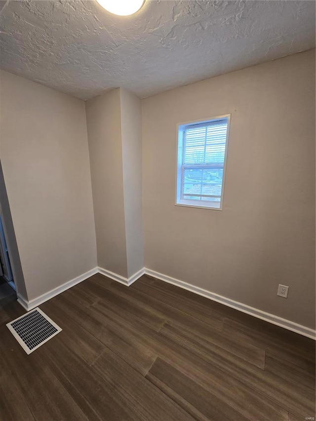 empty room featuring a textured ceiling and dark hardwood / wood-style floors