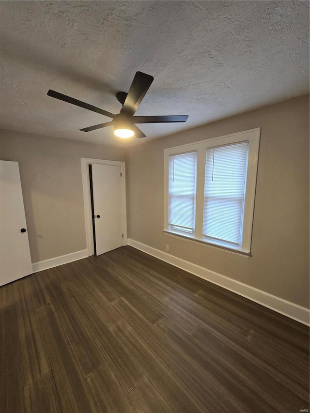 spare room featuring dark hardwood / wood-style floors, ceiling fan, and a textured ceiling